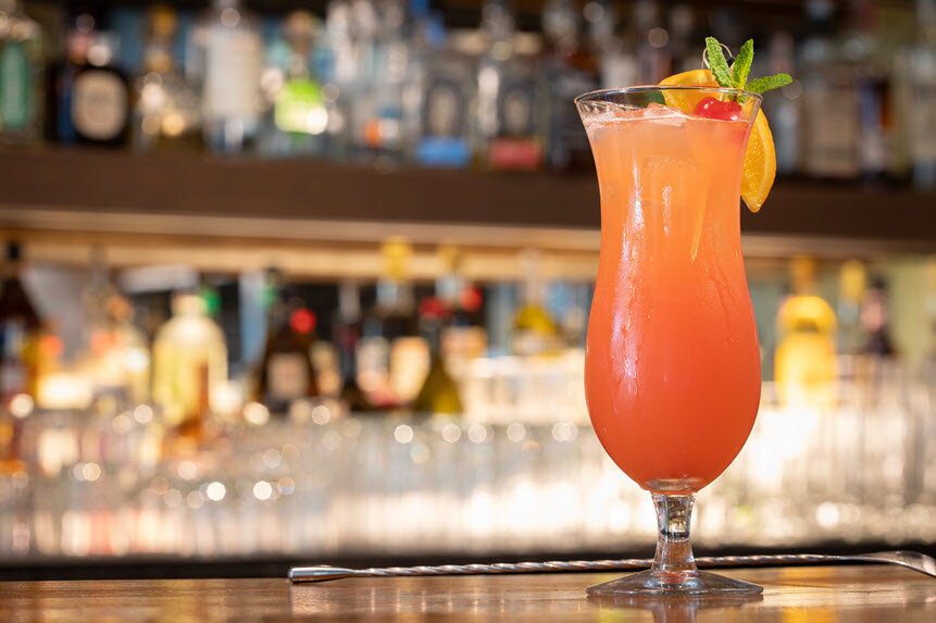 a glass of orange liquid with a fruit garnish