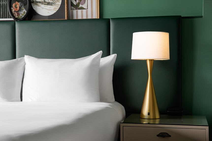 a lamp on a nightstand next to a bed