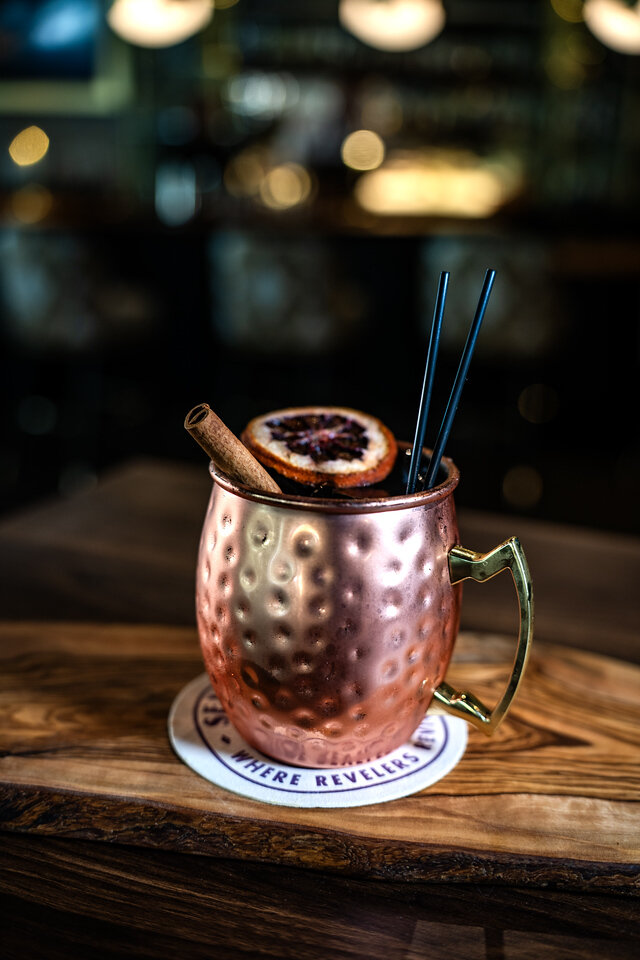 a copper mug with a slice of orange and cinnamon sticks