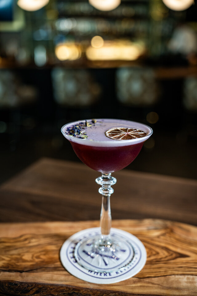 a glass with a purple liquid and a slice of lemon on top
