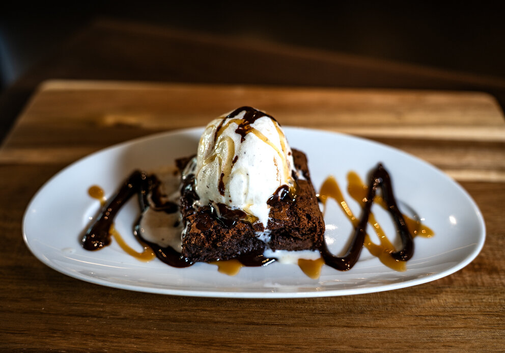 a brownie with ice cream and syrup on a plate